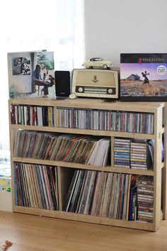 a record player sitting on top of a wooden shelf filled with vinyl records and cds