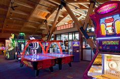 several arcade machines in a large room with wooden ceilinging and colorful carpeted floors