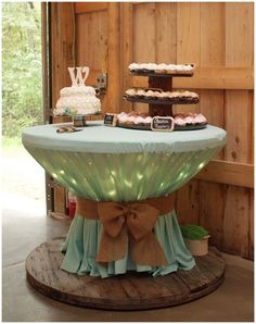 a table topped with cakes and cupcakes on top of a wooden floor next to a wall