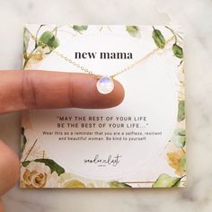 a hand holding a tiny necklace with a message on it that says, new mama may the rest of your life be the best of your life