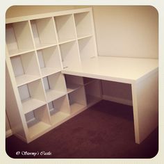 an empty white desk with shelves on the wall and carpeted floor in front of it