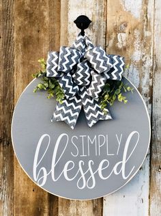 a gray and white sign that says simply blessed hanging on a wooden wall with flowers