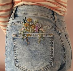 the back of a woman's jean pants with flowers on it and an orange striped shirt