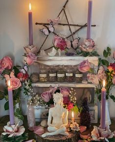 a table with candles and flowers on it, including a buddha statue in the center