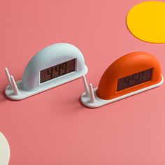 two alarm clocks sitting next to each other on a pink surface with circles around them