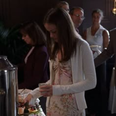 a woman standing in front of a cake with candles on it and people behind her