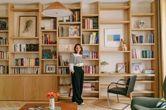 a woman standing in front of a bookshelf with many shelves full of books