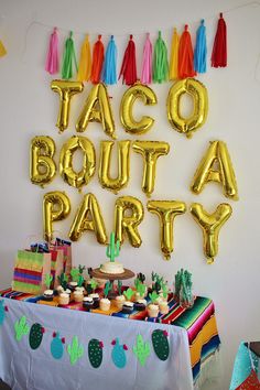 taco bouta party with balloons and cupcakes on the table in front of it