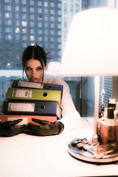 a woman sitting at a desk with stacks of binders in front of her face