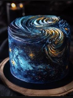 a blue cake with stars and swirls on it sitting on top of a wooden plate