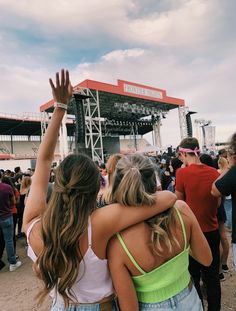 two girls hugging each other in front of an audience at a music festival or concert