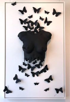 a group of black butterflies flying around a white framed art piece with a woman's face in the middle