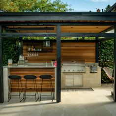 an outdoor kitchen with bar stools next to it