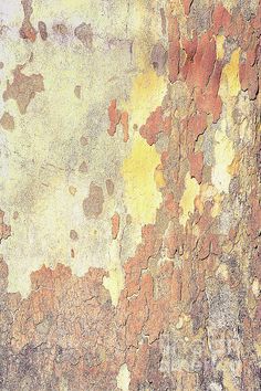 an old wall with yellow and brown paint on it's surface, peeling from the bark