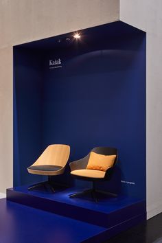 two chairs sitting on top of a blue platform in front of a wall with lights