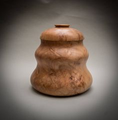 a wooden jar sitting on top of a white table next to a gray wall and floor