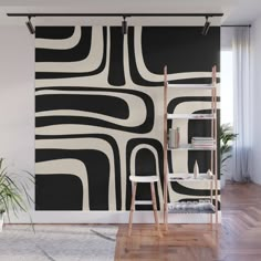 an abstract black and white wall mural in a living room with wooden flooring, ladders, bookshelf and potted plant