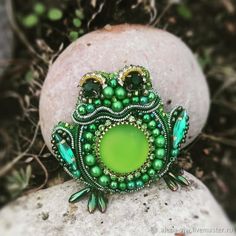 a green beaded frog sitting on top of a rock