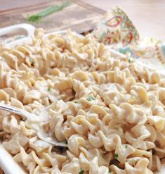 a white dish filled with macaroni and cheese on top of a colorful table cloth