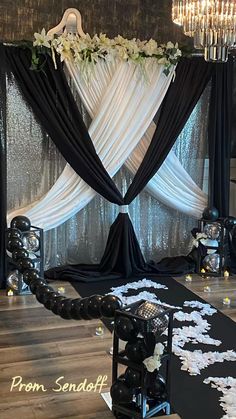 a black and white wedding ceremony setup with flowers on the floor, chandelier and drapes