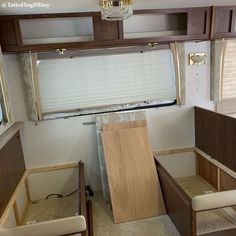 the inside of a recreational vehicle with wood cabinets and window coverings on each side