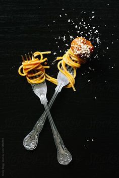 two forks with some food on them sitting next to each other by michela for stocks