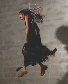 a woman in a black dress is flying through the air with her hair pulled back