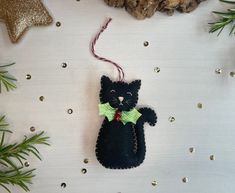 a black cat ornament hanging from a christmas tree with pine branches and other decorations