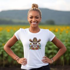 Saddle up and get ready to ride in our Cowboy Skull and Wildflowers Unisex Tee. This jersey short sleeve tee features a striking cowboy skull surrounded by vibrant wildflowers, paying homage to folk art design. Perfect for any cowgirl or cowboy, this tee seamlessly combines unique style with comfort, making it a must-have addition to your wardrobe. Giddy up and add a touch of Western flair to your look today. #15 Folk Art Classic unisex jersey short sleeve tee fits like a well-loved favorite. So Fitted T-shirt With Skull Graphic Print, Day Of The Dead Skull Print Short Sleeve Tops, Day Of The Dead Skull Print T-shirt, Day Of The Dead Skull Print Short Sleeve T-shirt, Cowboy Skull, Folk Art Design, The Wild West, Arte Popular, Prism Color