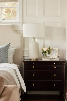 a bedroom with a bed, night stand and lamp on the nightstand next to it