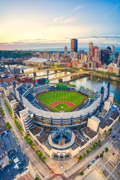 an aerial view of a baseball stadium with the city skyline in the background at sunset