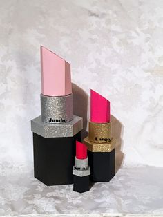 three lipsticks are stacked on top of each other in black and silver glitter boxes