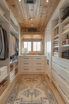 a walk - in closet with white cabinets, drawers and rugs on the floor