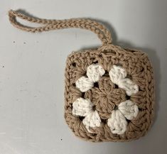 a crocheted square with four white flowers on the front and one brown in the back