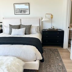 a white bed with black and gray pillows