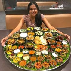 a woman sitting in front of a large platter of food