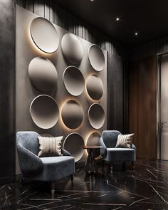 two chairs and a table in front of a wall with circular mirrors on the walls