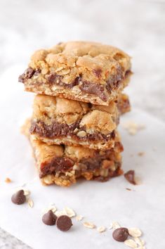 three chocolate chip bars stacked on top of each other with oats scattered around them