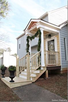 a small house with stairs leading up to the front door and entry way, decorated for christmas