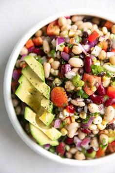 a white bowl filled with beans, avocado and other vegtables