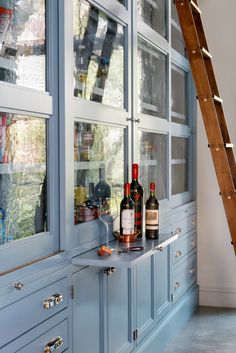 bottles of wine are sitting on the counter in front of a window with a ladder