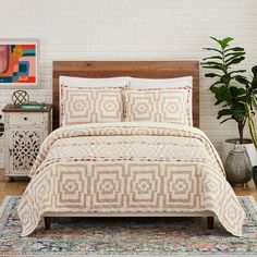 a bed in a room with a white brick wall and wooden headboard next to a plant