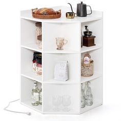 a white shelf filled with lots of bottles and glasses next to a coffee pot on top of a table