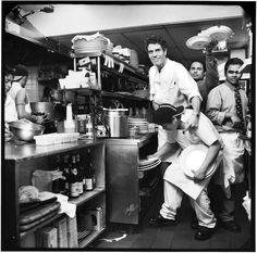 black and white photograph of men working in a kitchen with pots and pans on the counter