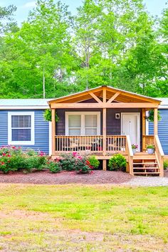 a blue mobile home with flowers and trees in the background