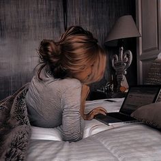 a woman laying in bed using a laptop computer