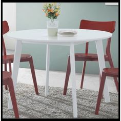 a white table with two red chairs and a flower vase on top of the table