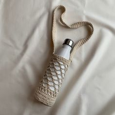 a crocheted water bottle bag on a white sheet with a silver lid and handle