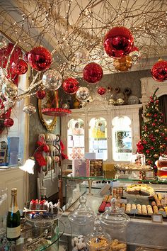 an assortment of desserts and pastries on display in a store with red ornaments hanging from the ceiling