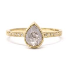 a yellow gold ring with a white diamond in the center and small diamonds around it